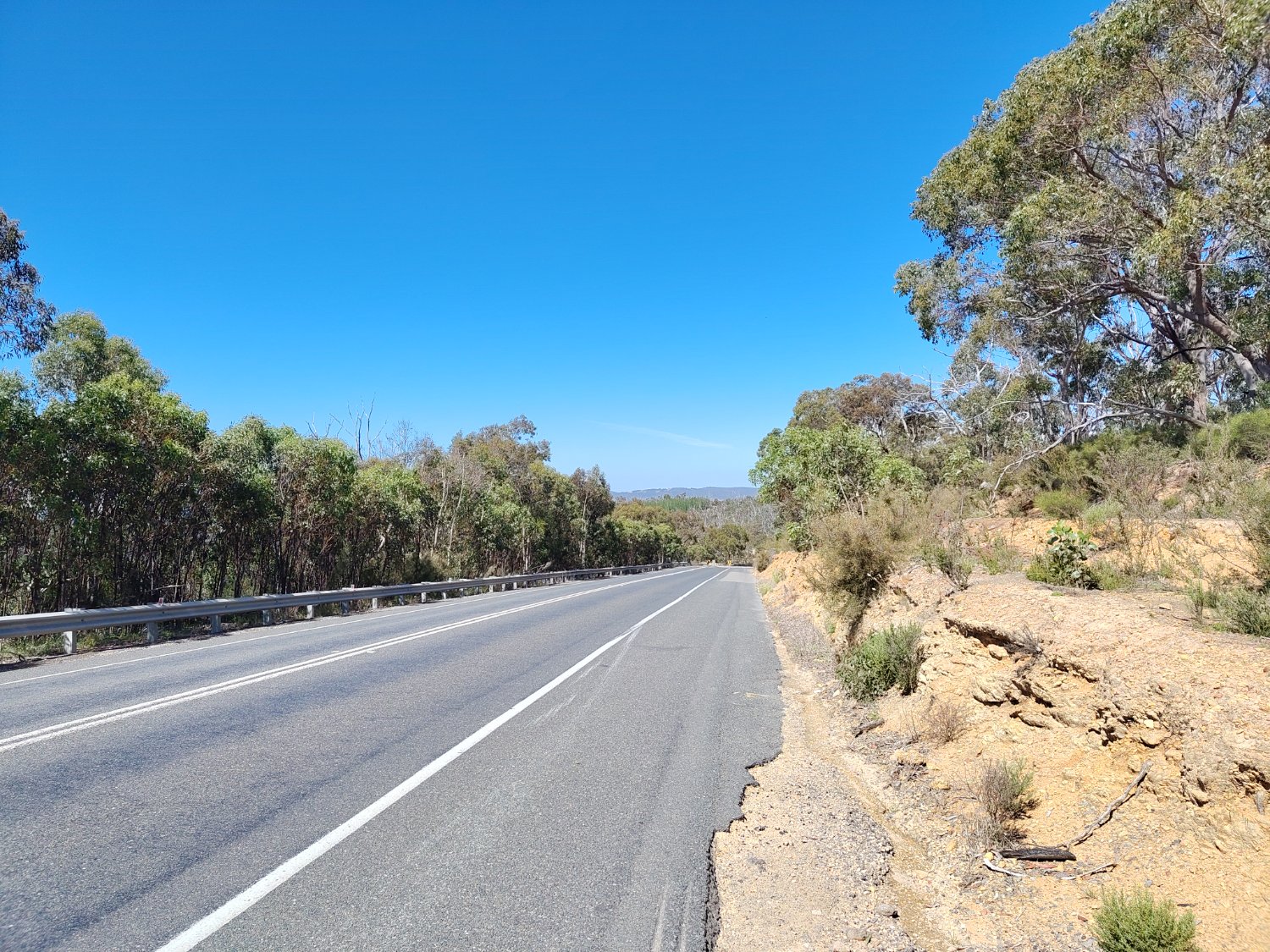 On the side of a road, looking down a long hill in the middle of nowhere